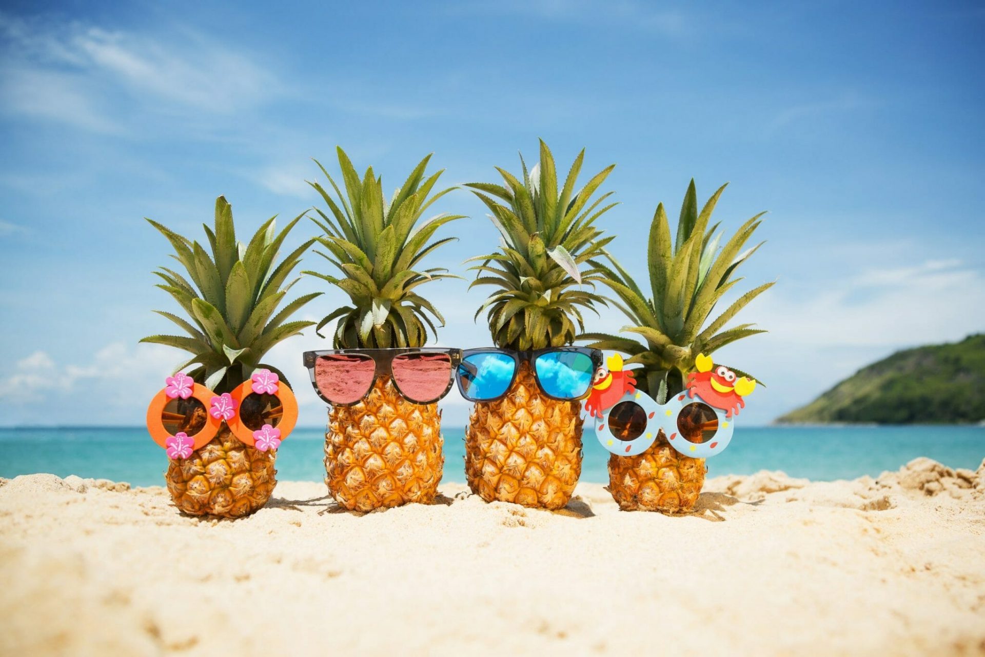 Ananas mit Sonnenbrille am Strand.