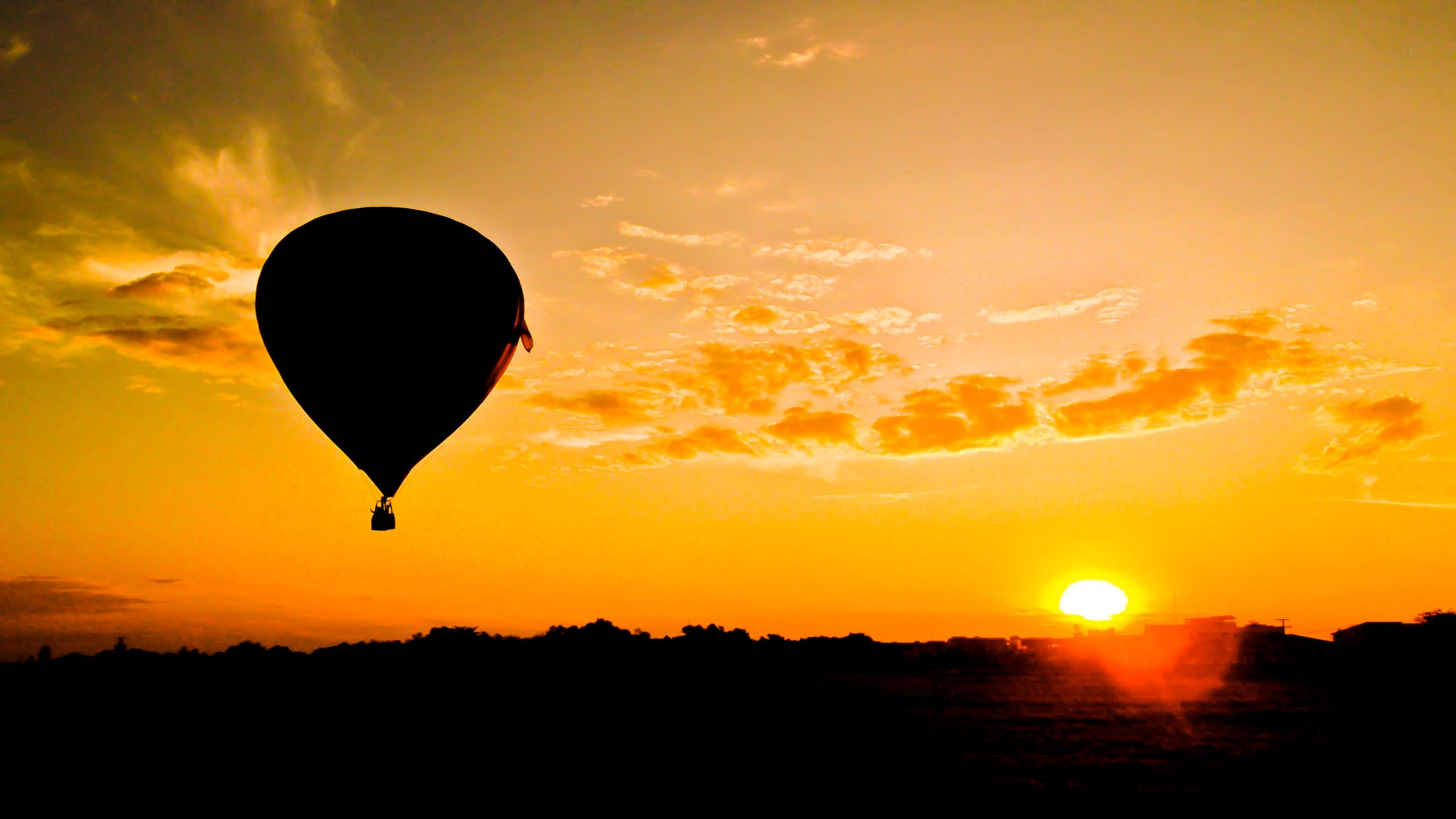 Beschatteter Heißluftballon mit Sonne im Hintergrund.