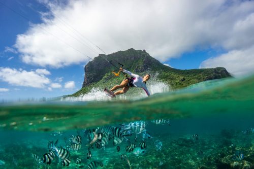 Kitesurfer mit der Hand im Wasser.