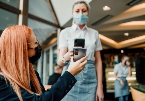 zwei Personen scannen gegenseitig ihre Handys, um zu zeigen, dass sie geimpft wurden.